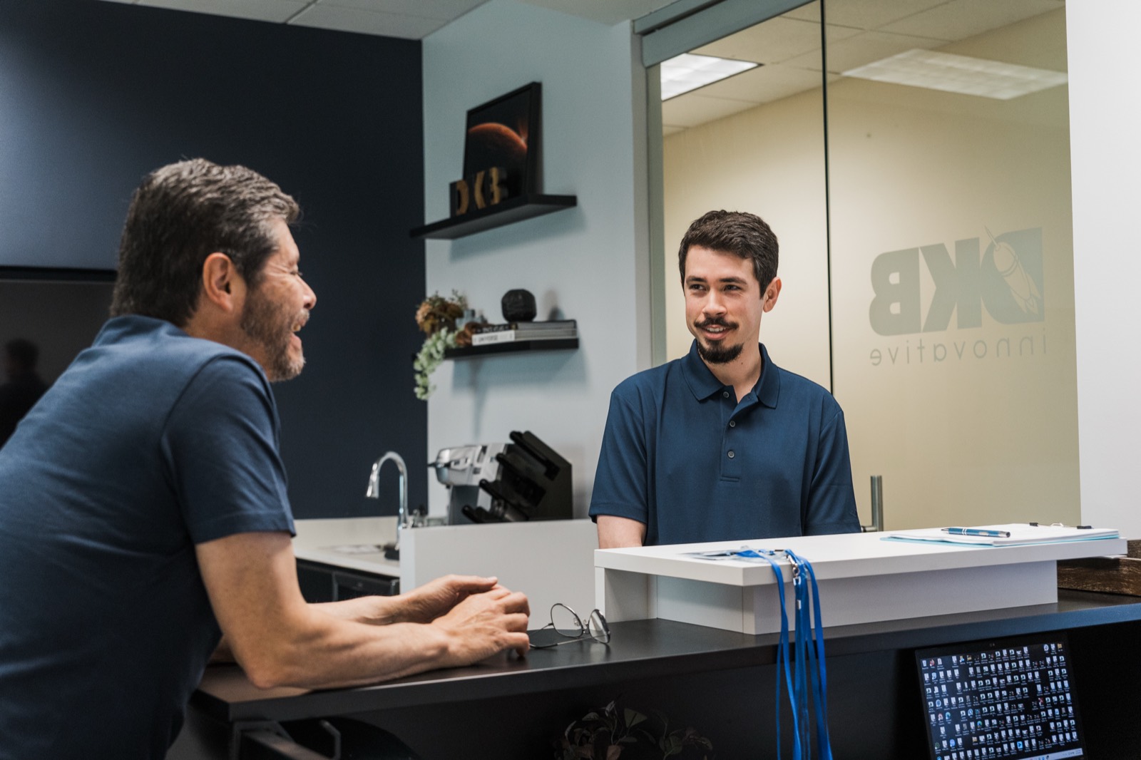 DKBinnovative team member assisting a client at the Frisco front desk, providing IT support for law and accounting firms